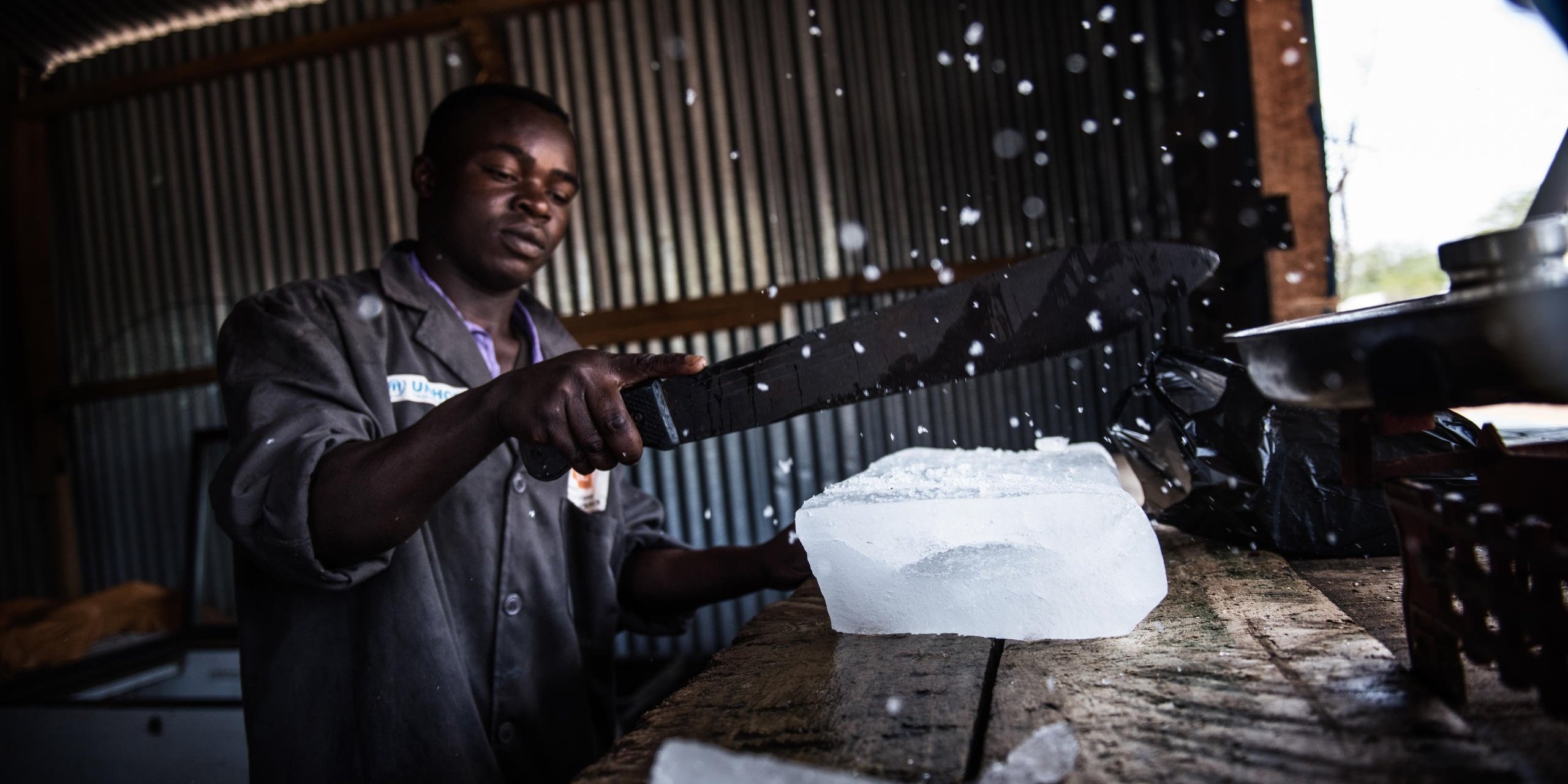 Abdikadar (28) is a manager at a small ice-making plant in Kenya’s Dadaab refugee camp. He is a Somali refugee.
Workers at the NRC-supported factory create ice and sell it in blocks to refugees in the camp. They also sell flavoured ice cold soft drinks. Abdikadar has a team of 12 young people working for him. He’s proud of their business.
The Hormud Youth Ice Plant has been providing jobs for young Somali refugees for 9 years. It was set up as part of NRC’s youth education programme. It is a one-year informal education plan designed to support young people affected by conflict, who have a lack of opportunities or missed out on school. Through the programme, youths acquire a marketable skill to increase their chances for finding employment. It includes crafts such as tailoring, journalism, hairdressing and welding.
….
Abdikadar’s parents are in Mogadishu. He is not interested in returning to Somalia because of the conflict.
Date: September 2016
Photo credit: NRC/ Fredrik Lerneryd