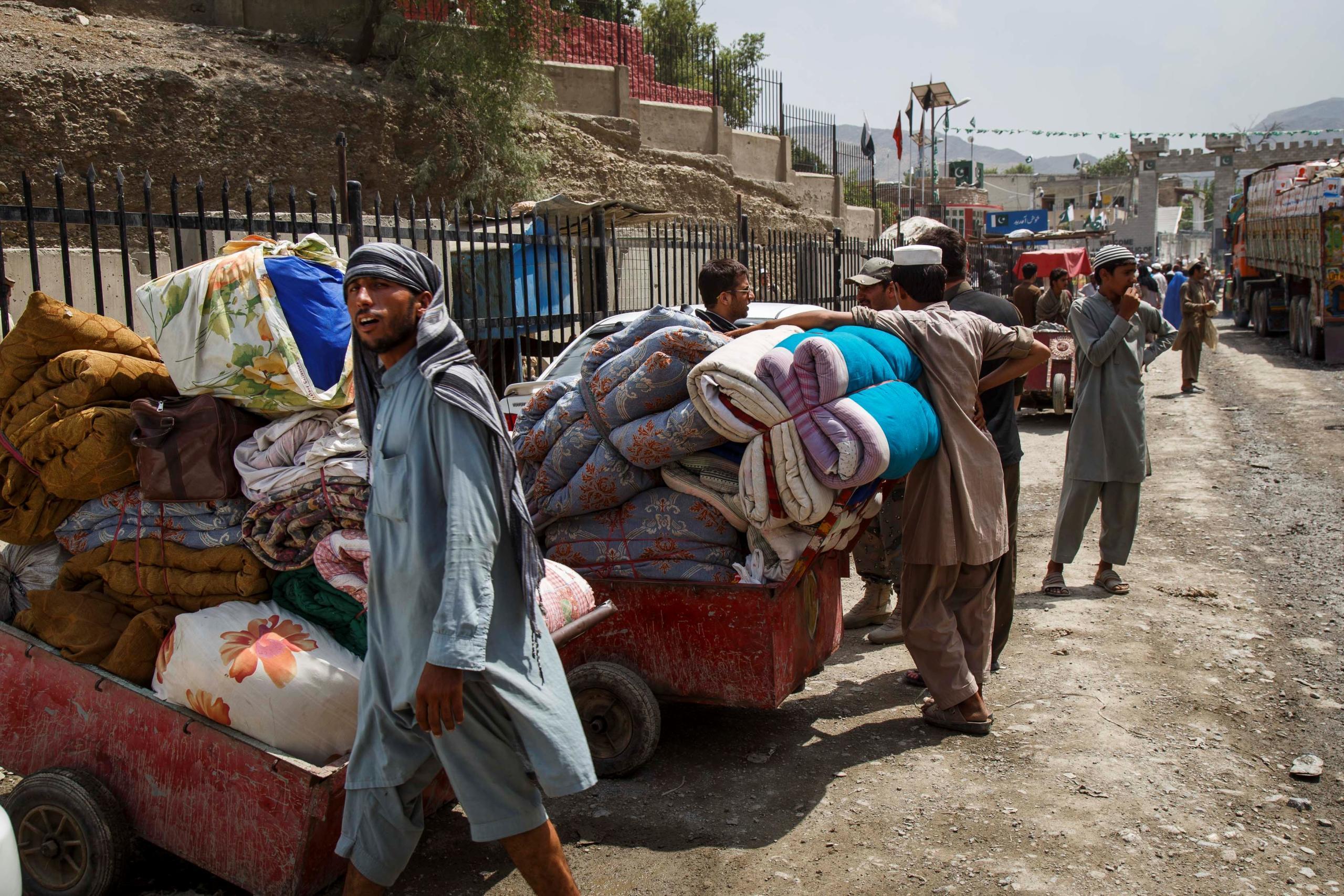 Some undocumented returnee families are too poor to afford lorry rental to transport their goods, and can only move what they can carry on public transport and by foot.  This family brings blankets and clothes through the Pakistan border by wheelbarrows.  Border staff estimate 40-60 returnee families cross without vehicles every day. (Photo: NRC/Jim Huylebroek)