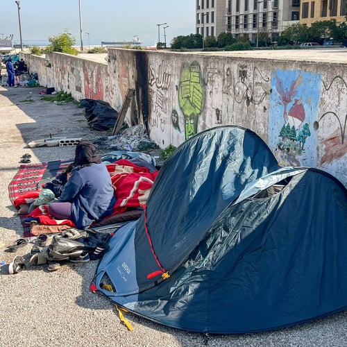 Fördrivna familjer sitter och vilar bredvid sina tillhörigheter utanför små tält längs en gata i Beirut.