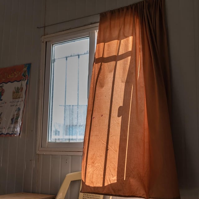A curtain gently blowing in the wind from an open window.