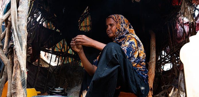 How the Middle east crisis is deepening hunger in Somalia. A woman is sitting on a jerrycan in her shelter, preparing food.