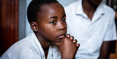 A boy rests his head in his hands.