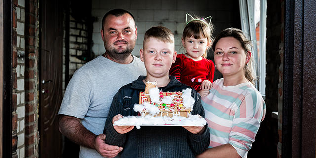 A Ukrainian family holding a gingerbread house