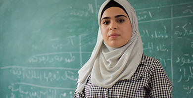 A young woman standing in front of a blackboard.