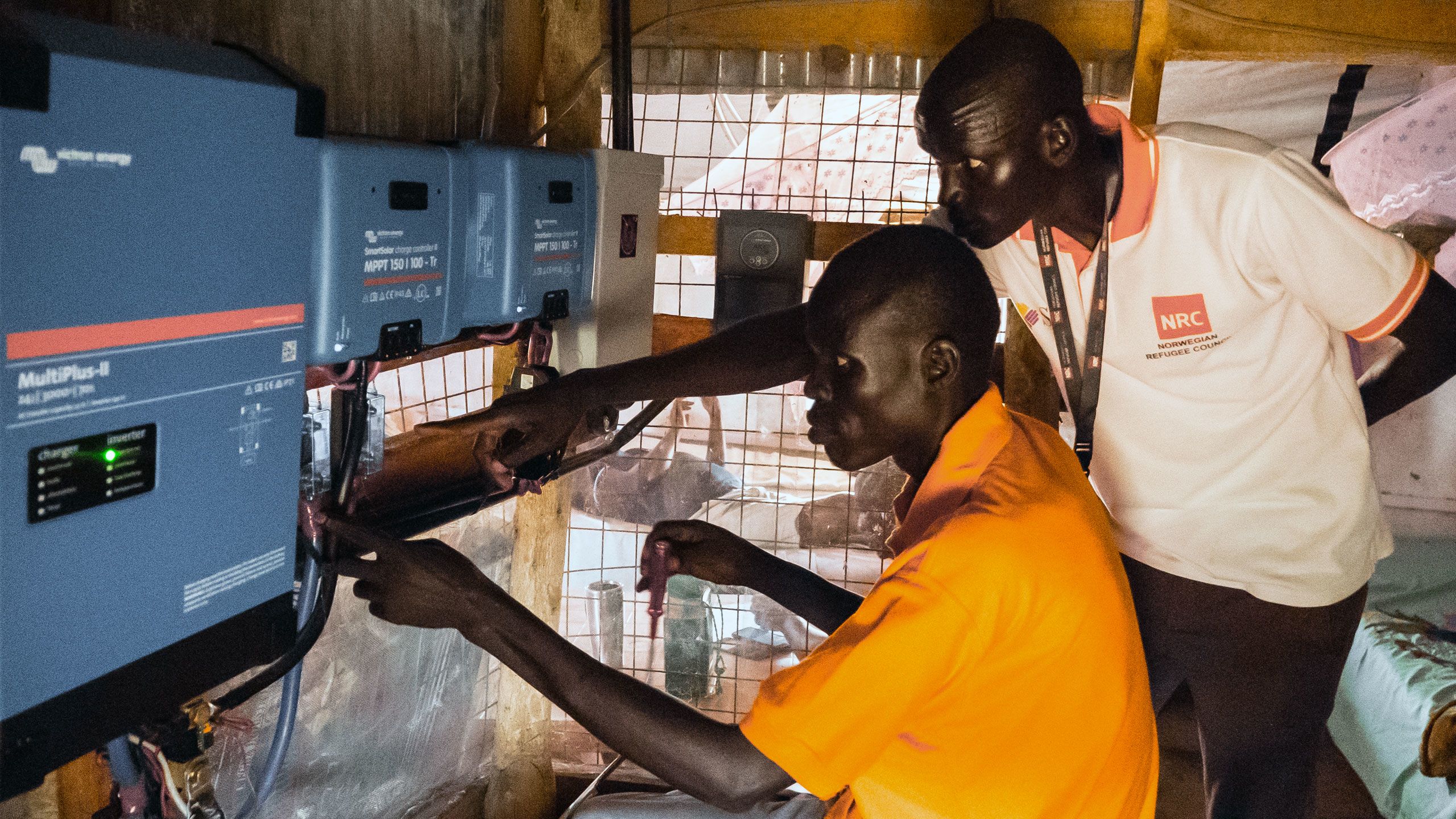 NRC staff check the battery boxes of the solar power system installed at the office in Mankien, South Sudan.
