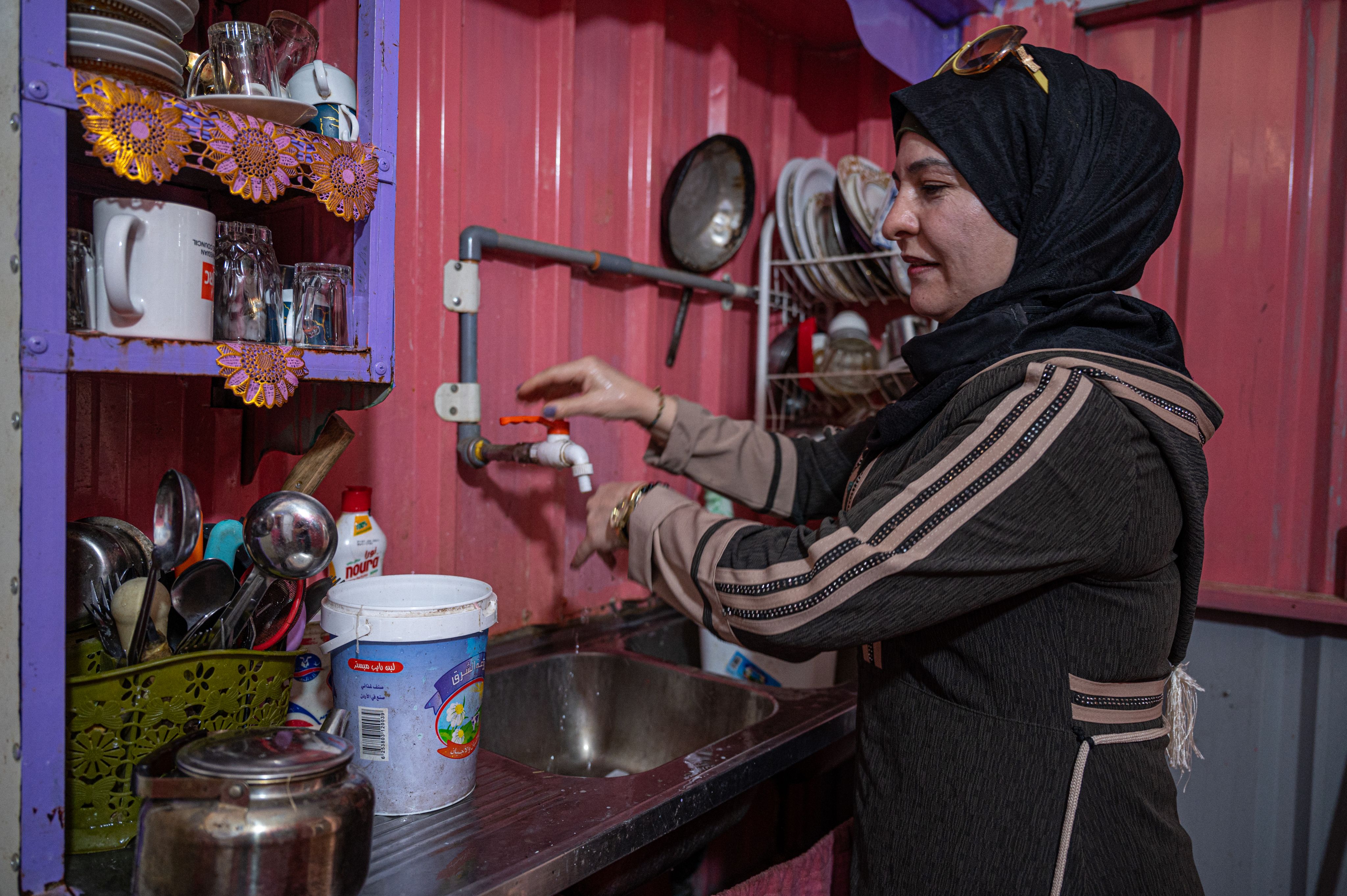 A Syrian woman washes her hands in the kitchen