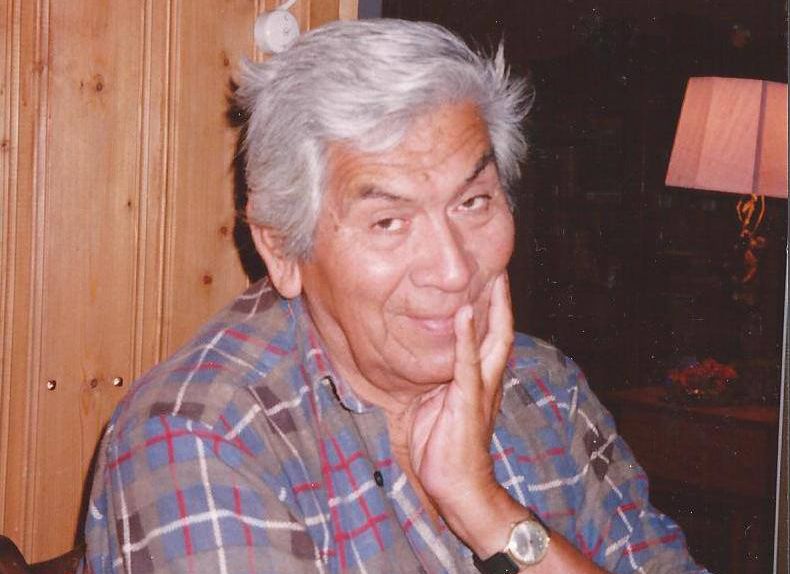 Alfredo's father, with his hand on his chin, smiling to the camera.