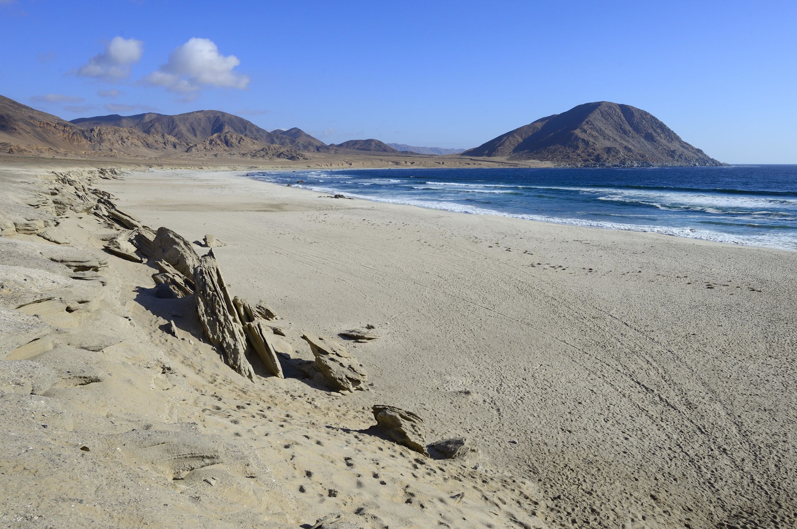 A long sandy beach stretches into the distance. The waves come rolling in.