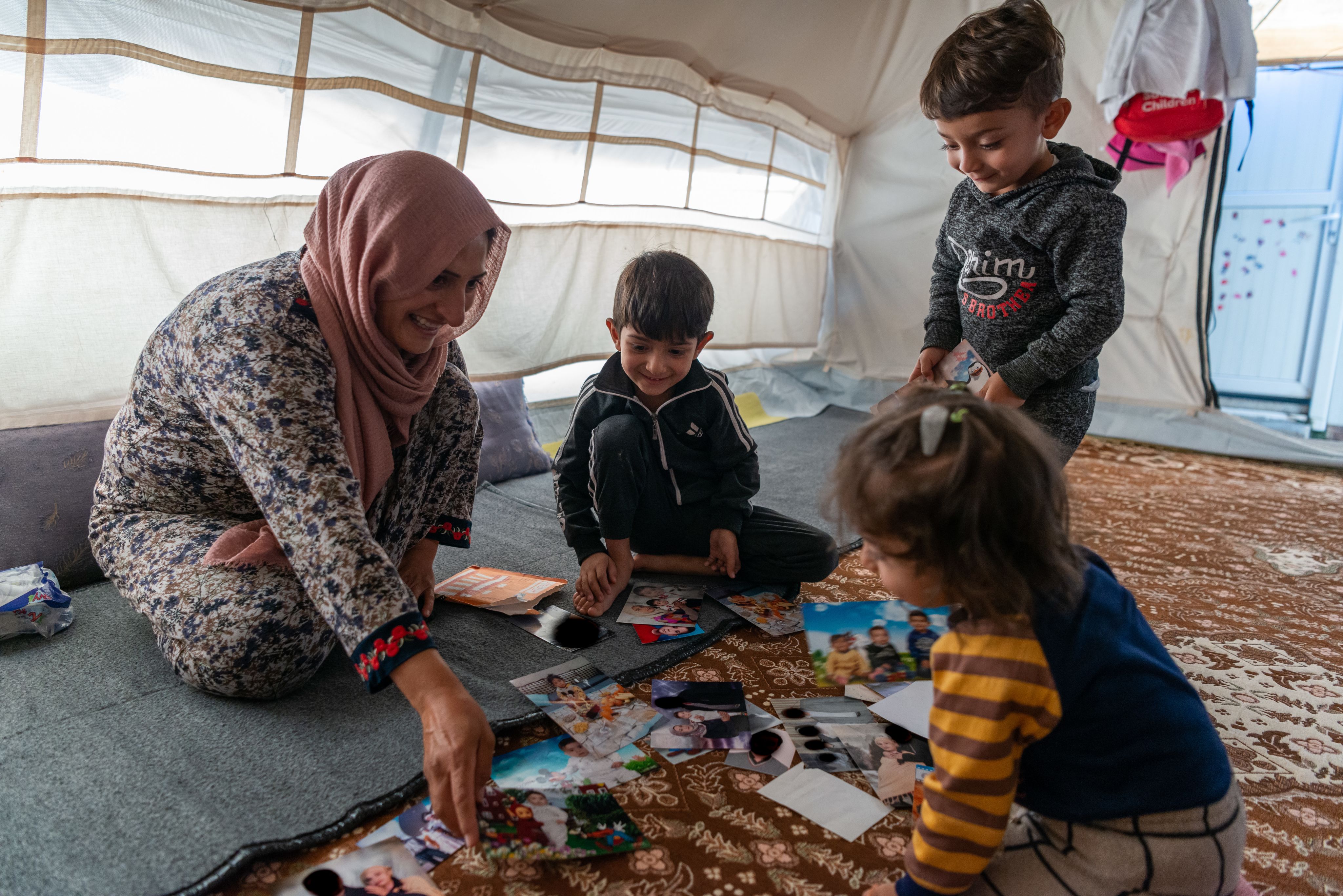 Woman and three children look at photos on the floor.
