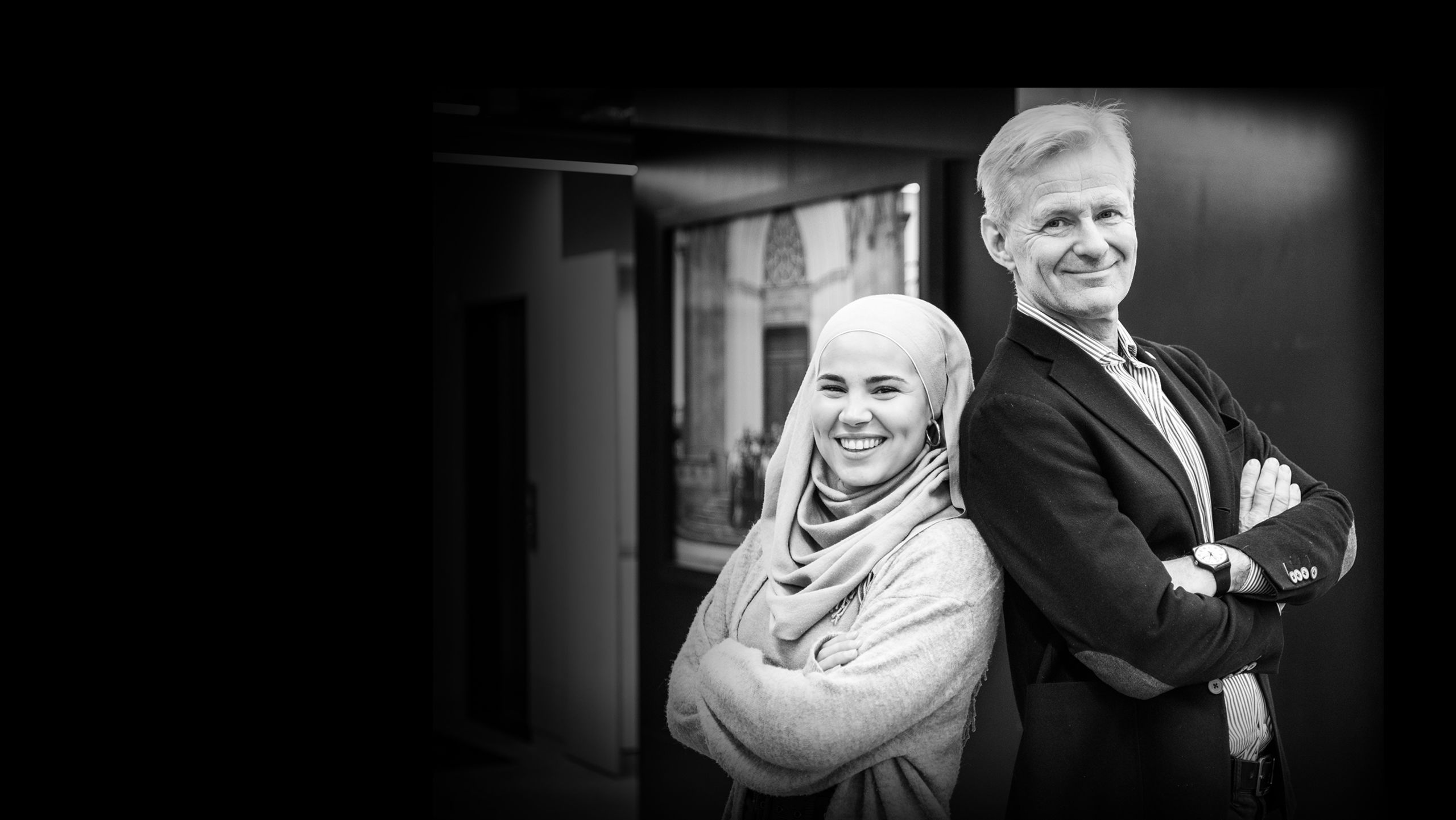 Iman Meskini og Jan Egeland står rygg mot rygg og smiler til kameraet.