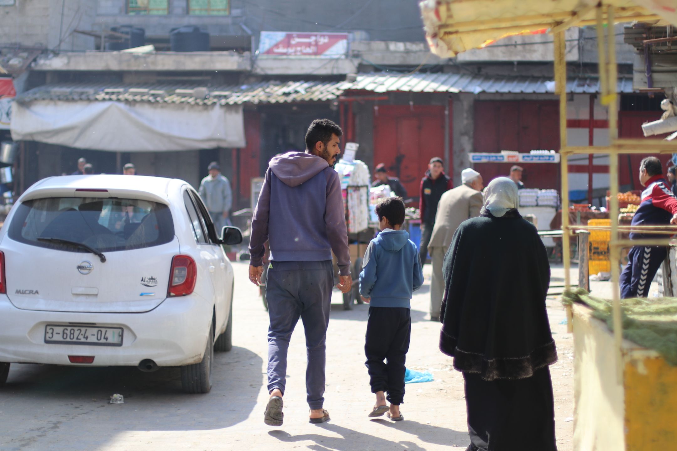 A boy and father walk in a market.