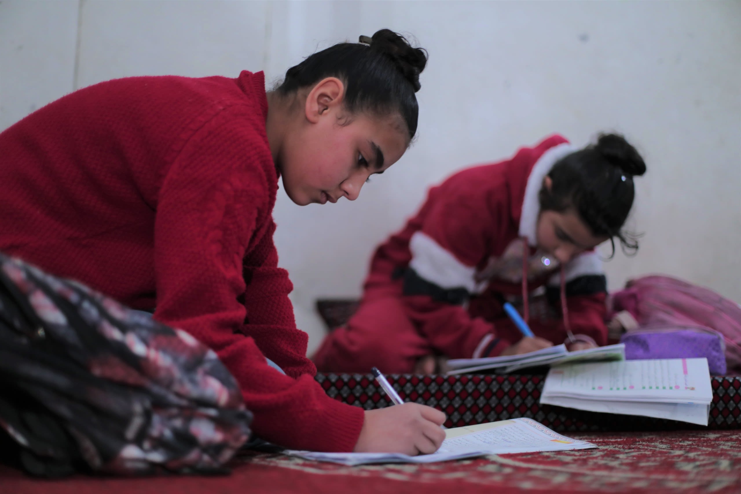 Two children do homework on the floor.