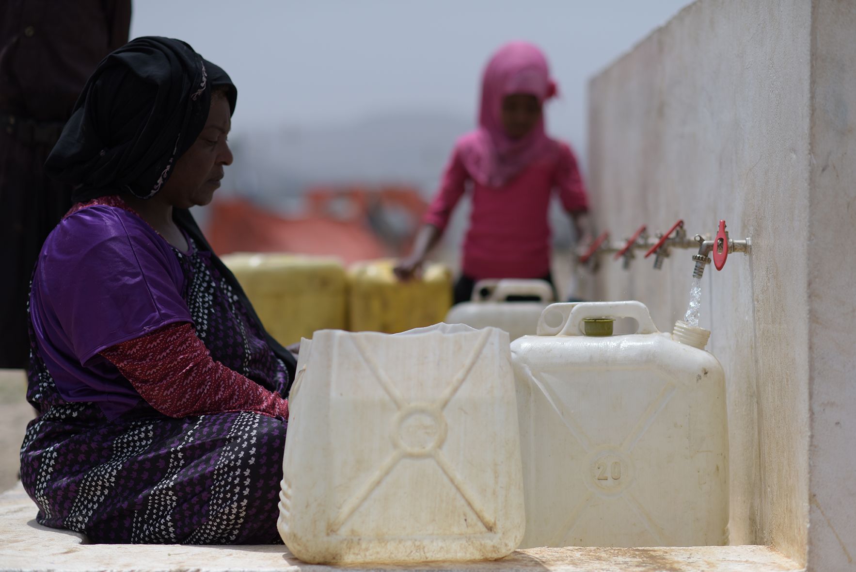 En kvinna fylla vatten i dunkar.