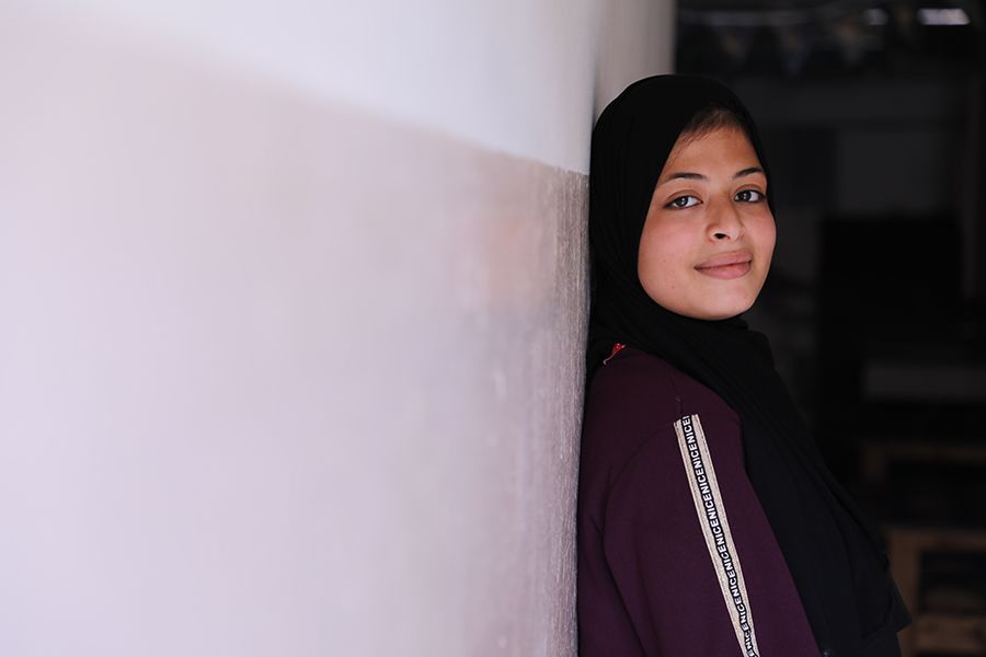 Omaia leaning against a wall, smiling.