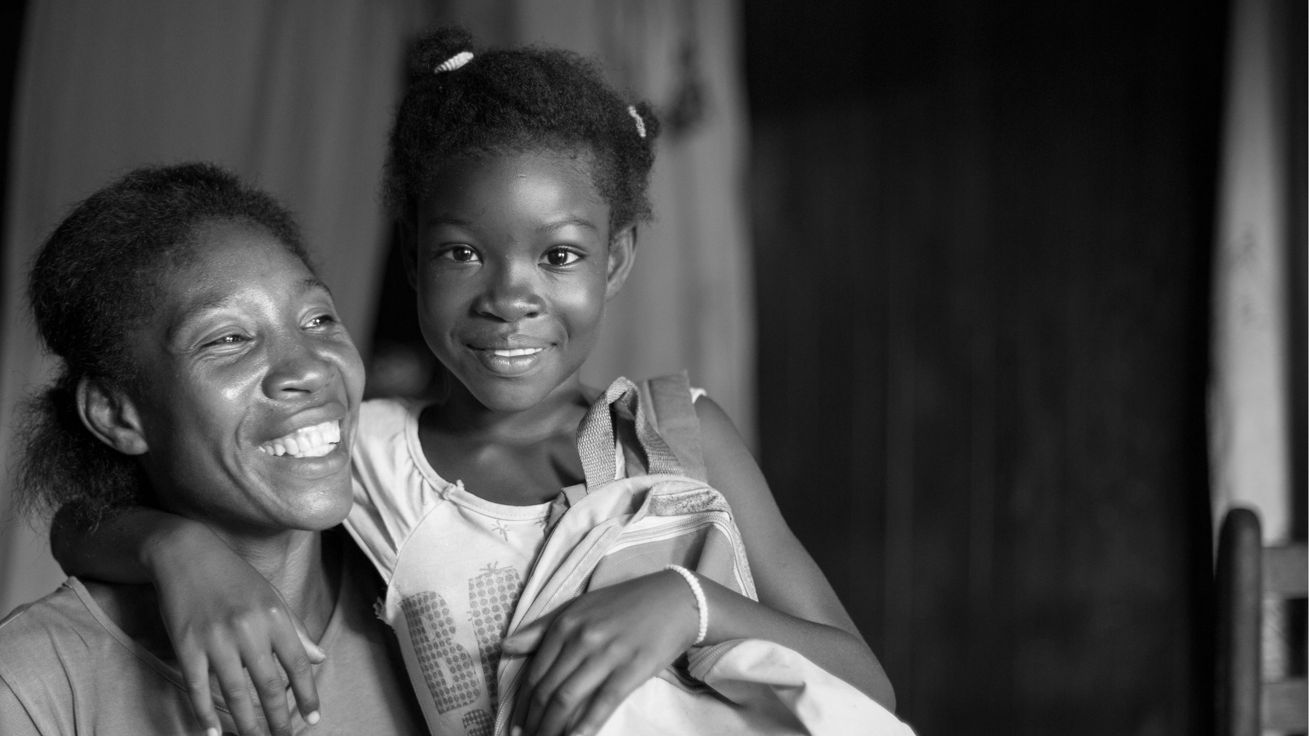 A mother and daughter laughing. The daughter has her arm around her mother's shoulder.