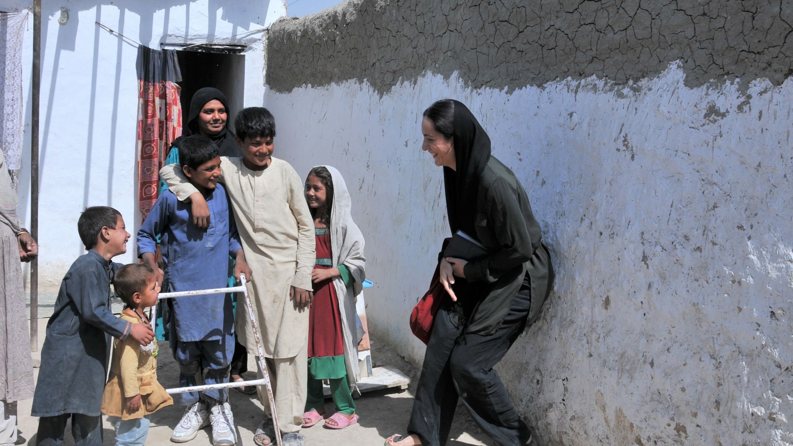 A group of people laughing. They have their arms around each other.