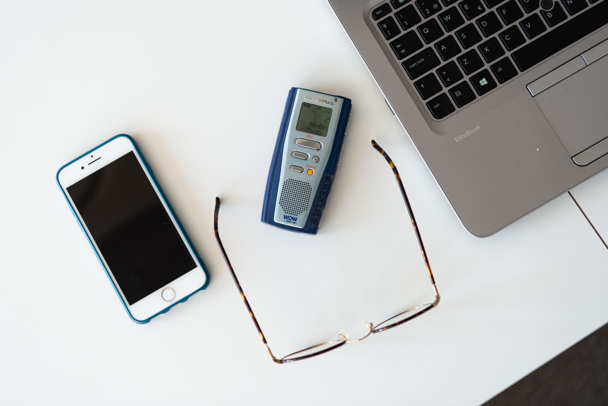 A phone, a pair of glasses, a recorder and a laptop.