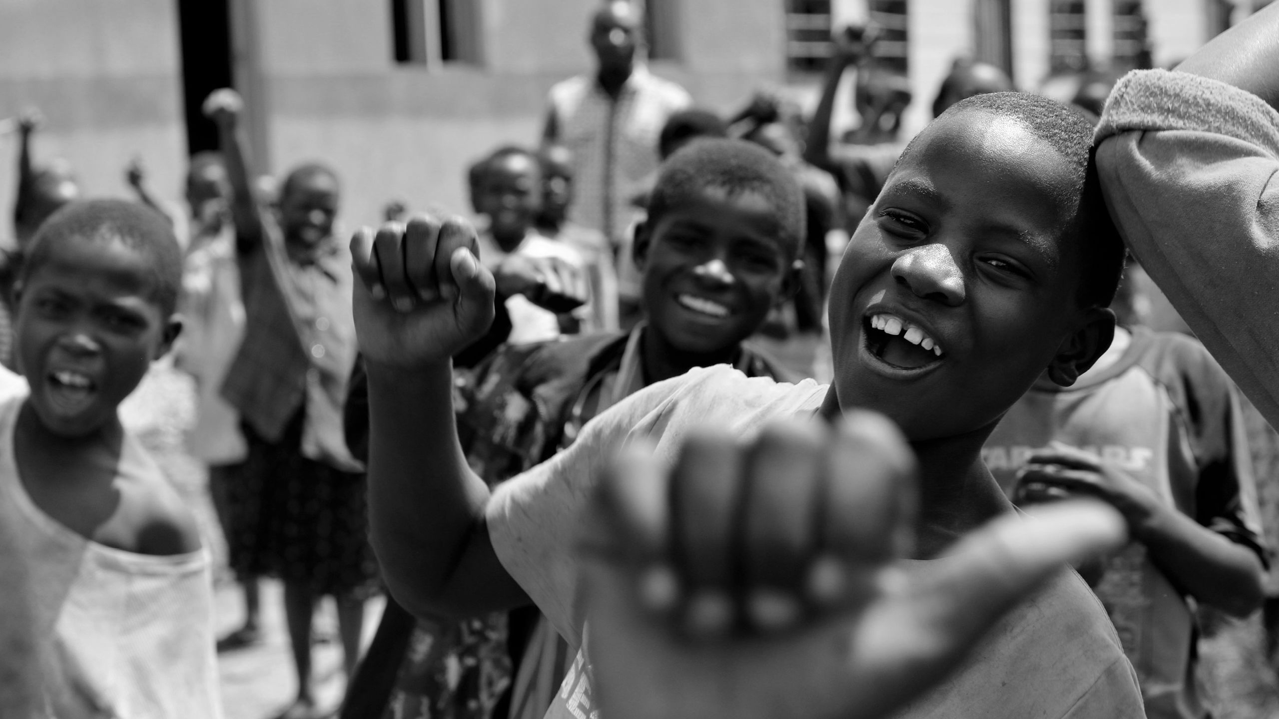 A group of children smiling and waving to the camera.