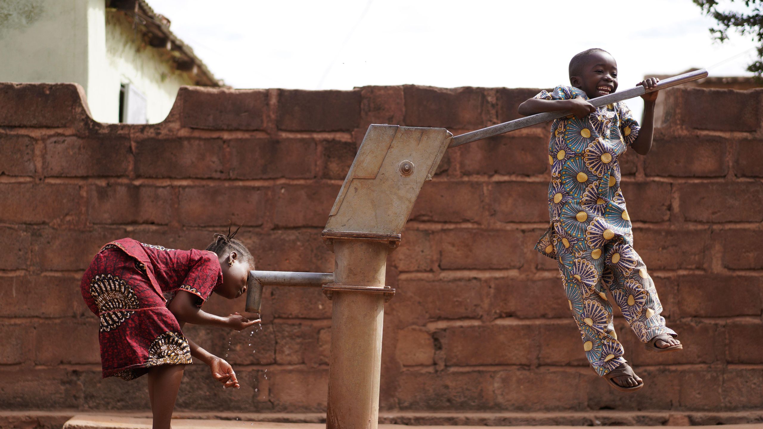 Two children playing by the village water pump