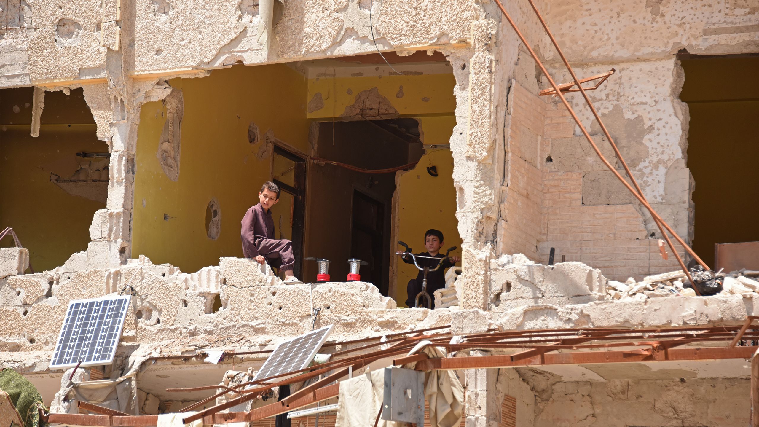 Two young boys playing in a destroyed building.
