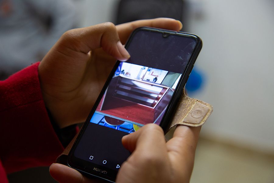 A woman is showing a photo of a cabinet on her mobile phone. She is holding the phone with both hands.