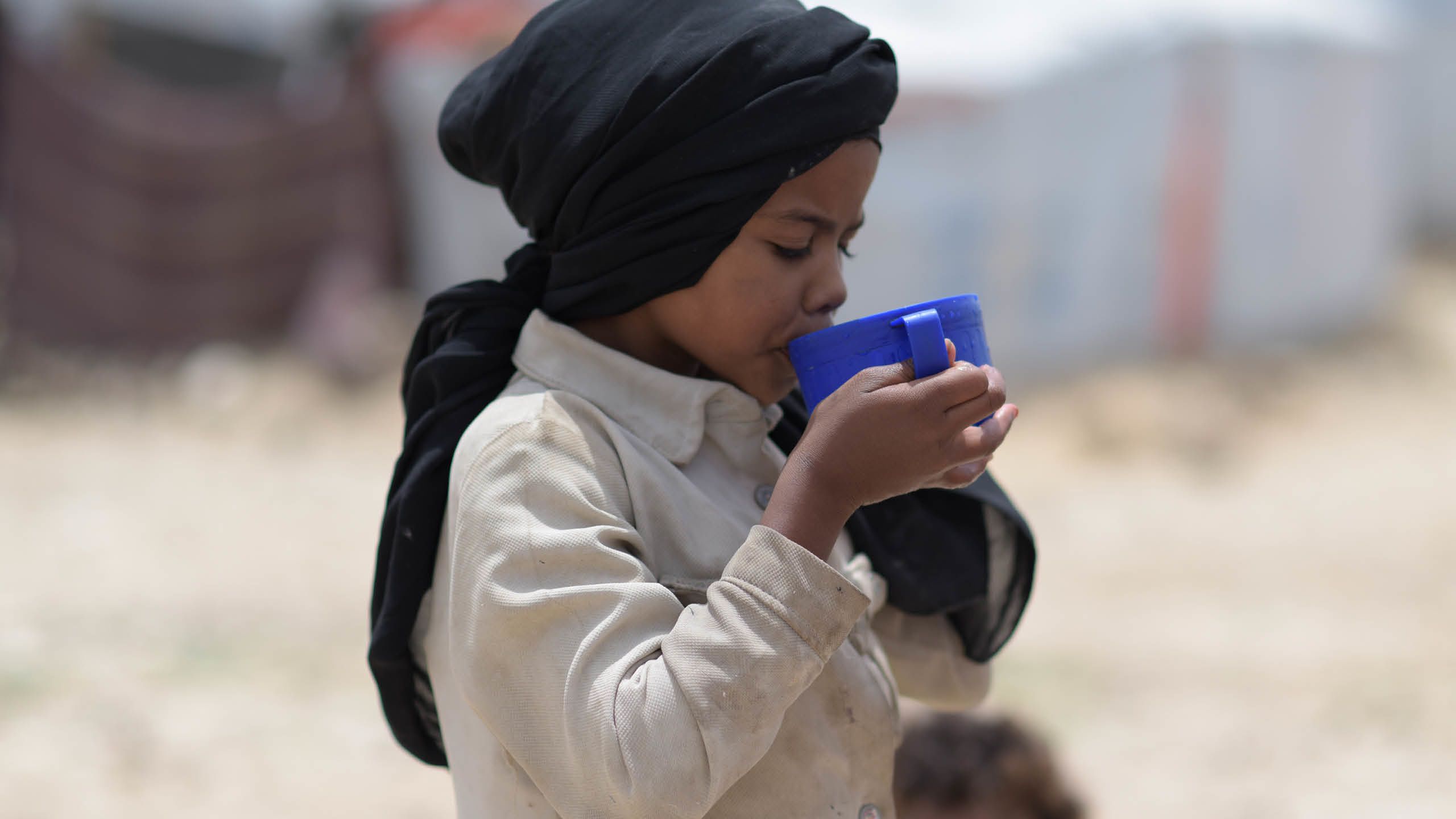 Boy drinking water from a blue cup